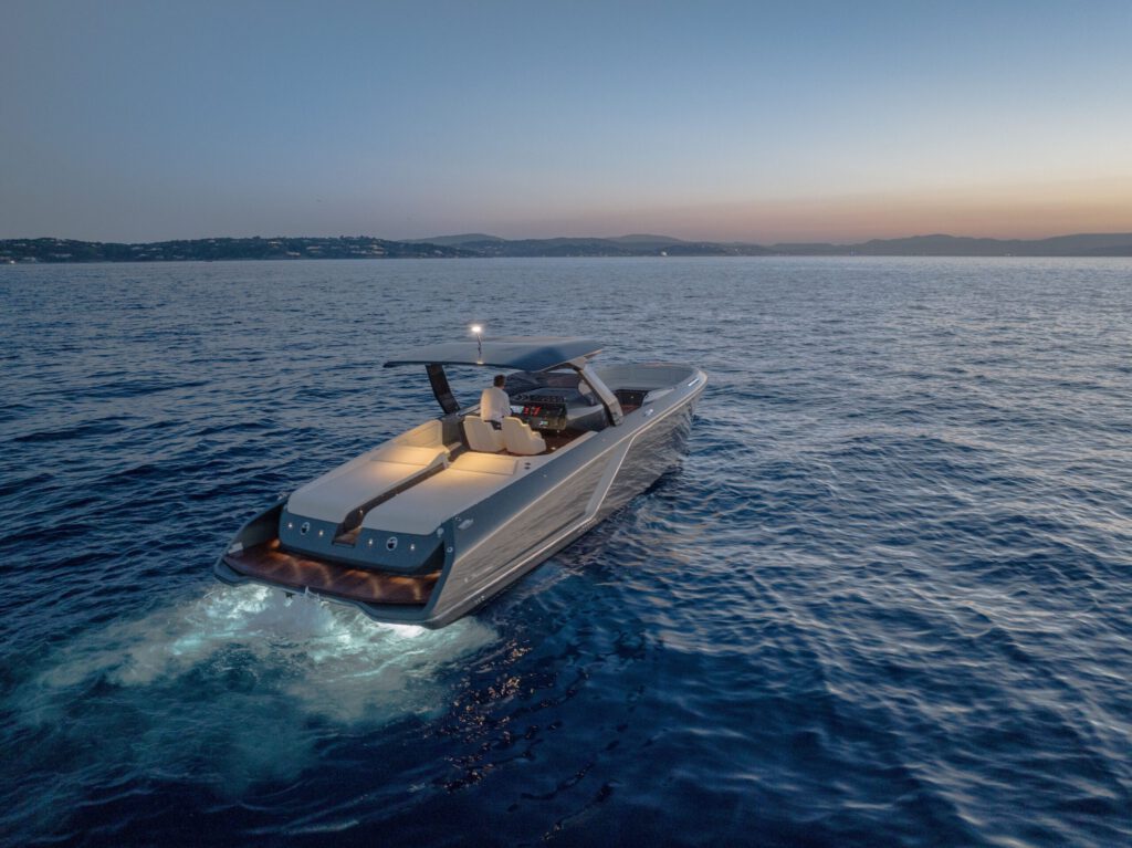 Luxuriöses Motorboot Frauscher 1212 Ghost Air bei Nachtfahrt auf offener See, mit leuchtender Beleuchtung und einem Steuermann an Bord.